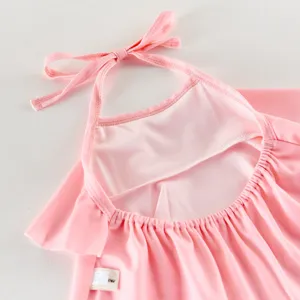 Rosa Neckholder Kinder Badeanzug Detail mit Rüschen und Rückenbändchen. Stoff Nahaufnahme.