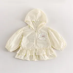 Détail de veste à capuche bébé légère, cardigan jaune pâle avec jolie fleur et ourlet à volants.