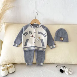 Détail en gros plan du gilet de bébé en tricot montrant les boutons texturés et broderies.