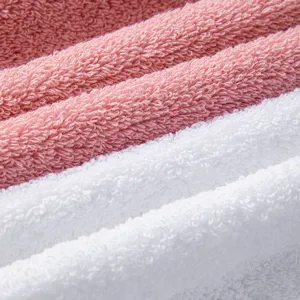 Premium plain cotton towel set close-up showing soft terry loop texture in pink and white.