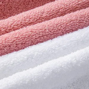 Texture de drap de bain en pur coton doux, gros plan, tissu éponge bouclé rose et blanc.