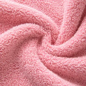 Gros plan d'une douce serviette de visage en coton rose avec texture bouclée moelleuse.