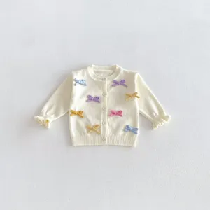 Close-up detail of cute baby girl knit cardigan with colorful mini bows and ruffles.
