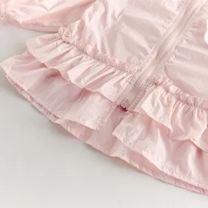 Vue détaillée d'un gilet rose pour bébé avec de jolies volants et fermeture éclair légère.