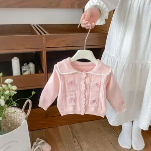 Pink knitted baby cardigan detail showing cute bow embroidery and sweet collar.