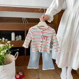 Detailed close-up view of baby girl striped knitted cardigan and cute flare jeans.