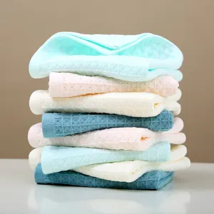 Serviettes en coton gaufré empilées aux couleurs pastel, douces et absorbantes.