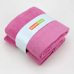 Ensemble de serviettes de bain en jacquard de coton rose, plié proprement avec bande de marque.