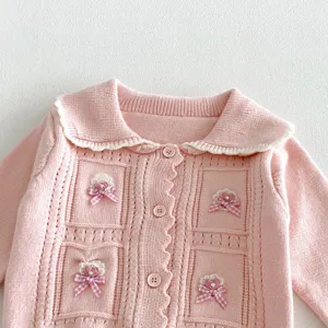 Pink baby girl knit cardigan detail, cute doll collar and sweet bow decoration texture.