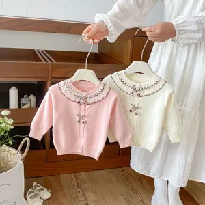 Detailed view of kids knit cardigan with lace collar and cherry buttons, sweet baby sweater top.