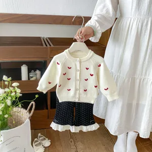 Primo piano dettaglio del cardigan in maglia da neonato con ricami a cuore e pantaloni.