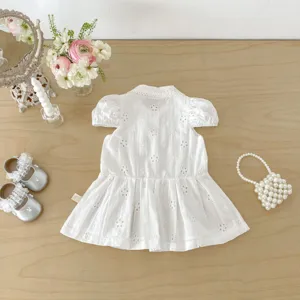 Détail de robe d'été blanche pour bébé fille avec broderie anglaise, style princesse chic.
