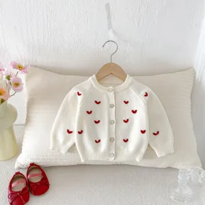 Vista dettagliata del cardigan in maglia per neonati con ricami di cuori rossi e bottoni.