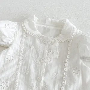 Gros plan d'un chemisier blanc pour fille brodé anglais avec col à volants et boutons floraux.