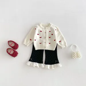Dettaglio del set cardigan in maglia per neonata con ricamo a cuore e pantaloni a zampa.