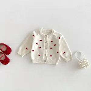 Vista dettagliata del morbido cardigan in maglia per neonati con ricamo a cuore rosso.