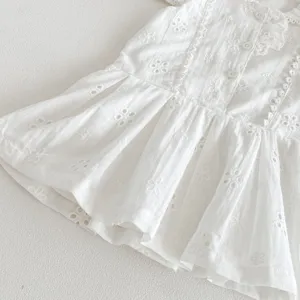 Vue de detail rapprochee de robe bebe fille blanche avec broderie anglaise et boutons fins.