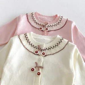 Detailed close-up of cute toddler knit cardigan featuring delicate ruffle collar and sweet cherry bow accents.
