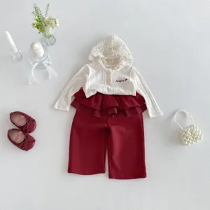 Detailed flat lay of baby girl lace-hooded ribbed top and ruffle pants set with cute accessories.