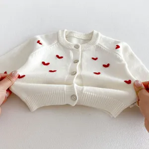 Dettaglio cardigan lavorato a maglia neonato, maglione bianco con ricami di cuore
