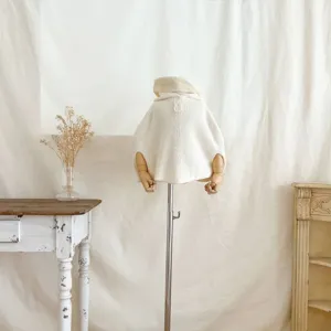 Detalle capa de punto para bebé, suéter blanco crema con capucha, ropa adorable para niños pequeños.