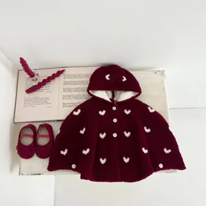 Detalle de capa con capucha de terciopelo para bebés, capa de punto roja con corazones blancos.