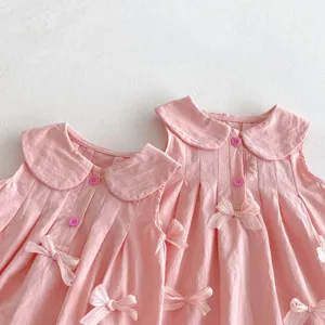 Detalle de cerca de un lindo vestido sin mangas para bebé rosa con cuello y lazos.