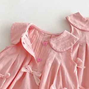 Precioso vestido de verano rosa para niña con lazos bonitos y cuello redondo, sin mangas.