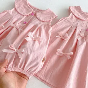 Primer plano del bonito vestido rosa para niña con diseño sin mangas, lazos y un tierno cuello.