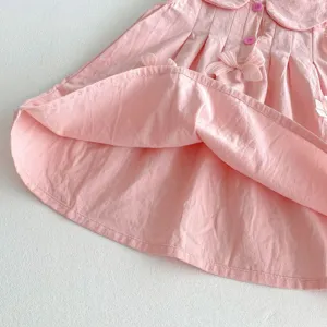 Detalle de vestido rosa para niña con lazo bonito, cuello solapa y botones de color rosa.