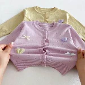 Detailed view of infant knit cardigan with cute heart and bow appliques, soft baby girl top.
