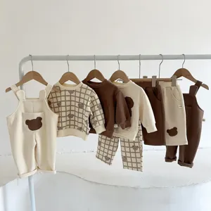 Detalle set ropa osito infantil, suéter y peto de dibujos animados en perchero.