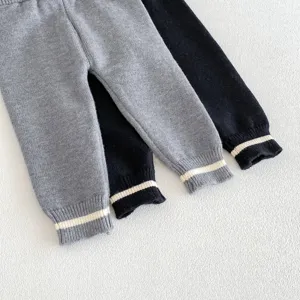 Detalle de hermoso pantalón de punto para bebé con puños de rayas en gris y negro