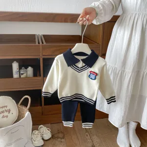 Knitted sweater set detail shot featuring contrast collar, striped cuffs, and vintage chest badge.