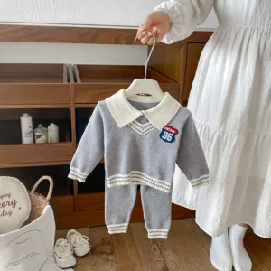 Detailed view of kids knitwear set, gray sweater with white collar and matching pants.