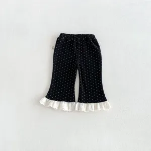 Close-up detail of girls black polka dot flared pants featuring delicate white lace hem trim.