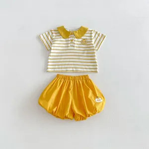 Dettaglio completo estivo per bambina, polo a righe e pantaloncini a palloncino gialli.