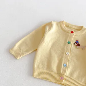 Close-up view of a cute yellow baby knitted cardigan with colorful buttons and dog embroidery.