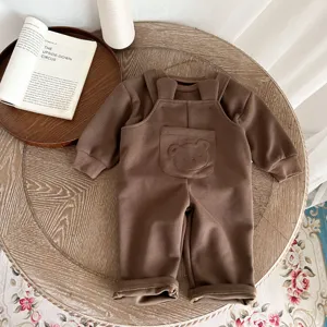 Primer plano del lindo conjunto de peto para bebé marrón con encantador diseño de bolsillo de oso.