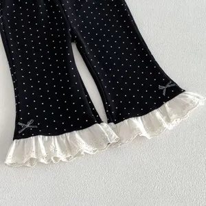 Detailed shot of toddler girls black polka dot flared pants with white lace cuffs and cute bows.