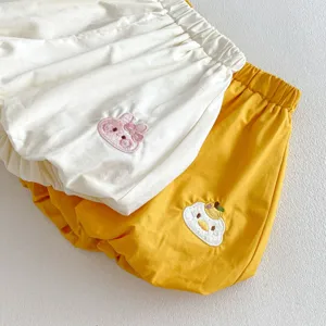 Dettaglio di pantaloncini da neonato con graziosi ricami di animali su tessuto morbido e confortevole.