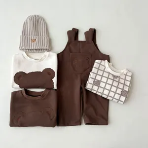 Detalle de conjunto casual de oso para bebé con sudadera, peto y gorro de punto.