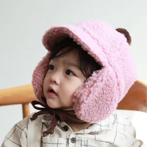 Detail view of pink plush baby winter earflap hat with cute brown strings and cozy texture.