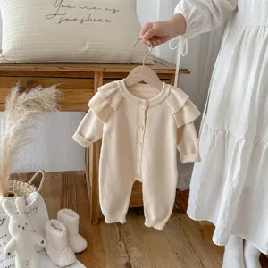 Cozy newborn knit romper detail, soft ruffle sleeves, cute wooden buttons, warm baby style lifestyle.