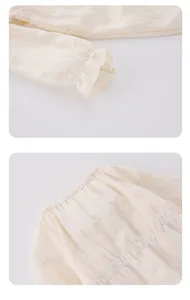 Gros plan detaille du romper a manches longues pour bebe fille avec de charmants noeuds brodes.