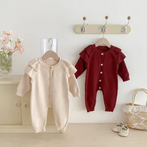 Infant baby knitted romper detail view showcasing the cute fly sleeves and wooden buttons.