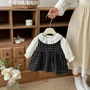 Completo primaverile per ragazze con camicetta con colletto a bambola bianco e abito gilet a quadri.