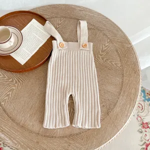 Detailfoto van de gebreide baby-overal met zachte ribtextuur, leuke knoopjes en handige bretels.