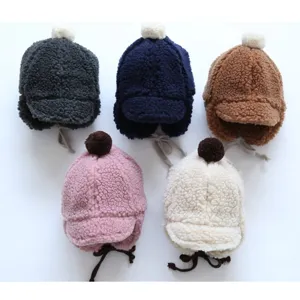 Plush earflap baby hat detail showing soft teddy fleece texture and warm pom-pom design.