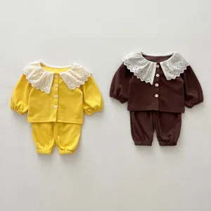 Detailed view of infant waffle knit two-piece set with white lace collar and buttons.